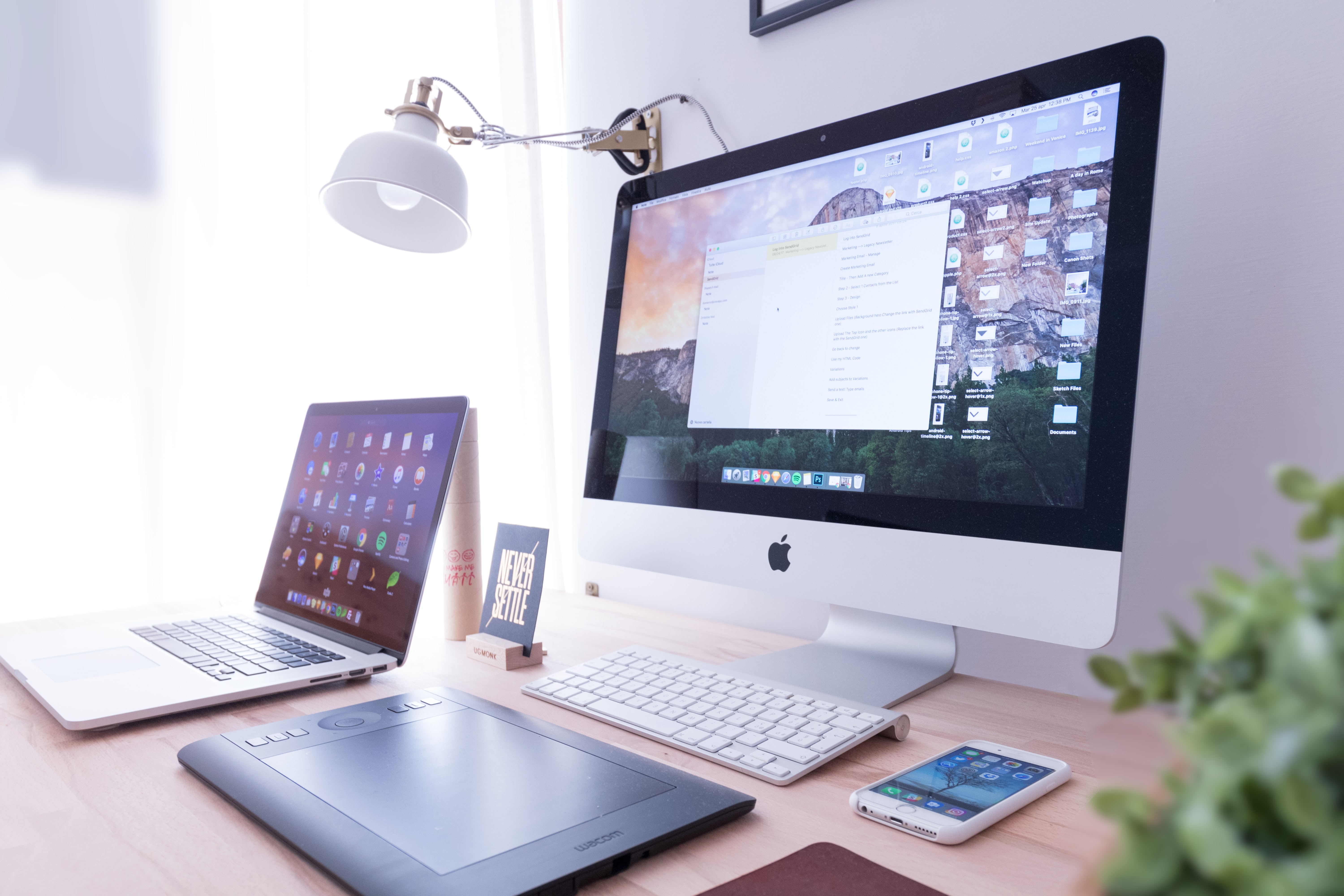 Laptop computer on a modern, black desk with a larger monitor screen in the background.